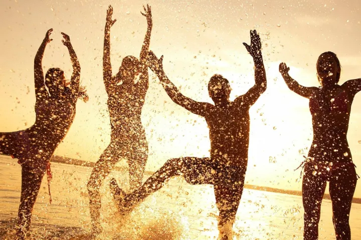 people splashing & playing on beach at sunset