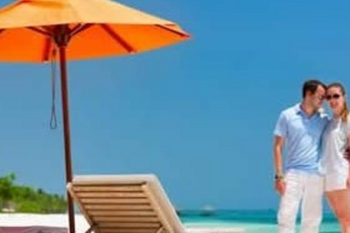 couple on beach next to umbrella