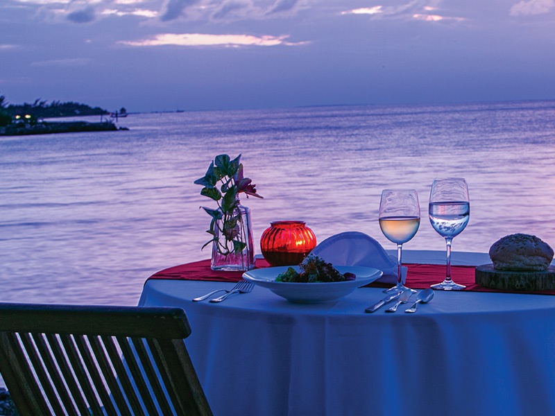 table set with dinner and wine along beach